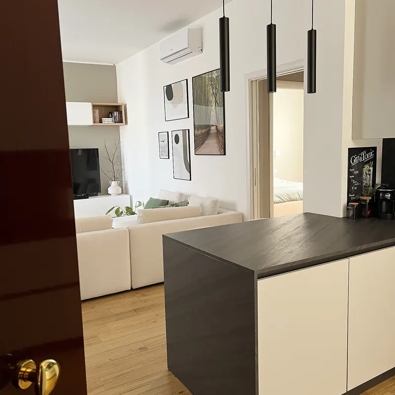 Cocina abierta al salón con isla y encimera oscura tras una reforma integral