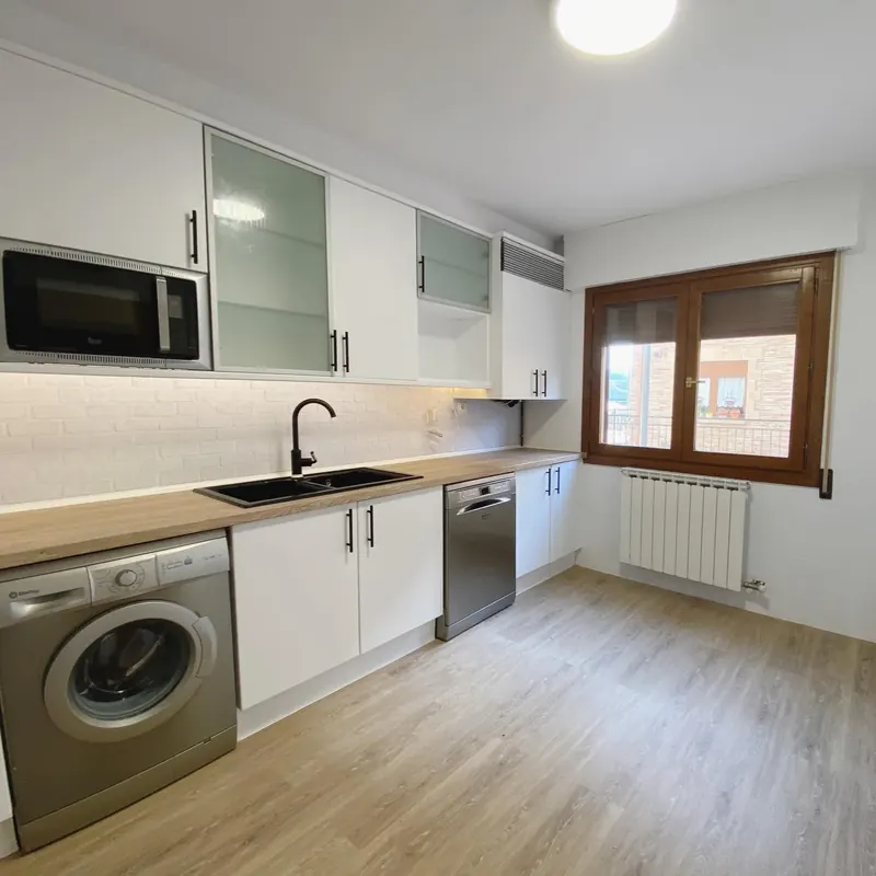 Cocina reformada con muebles de madera clara y electrodomésticos integrados