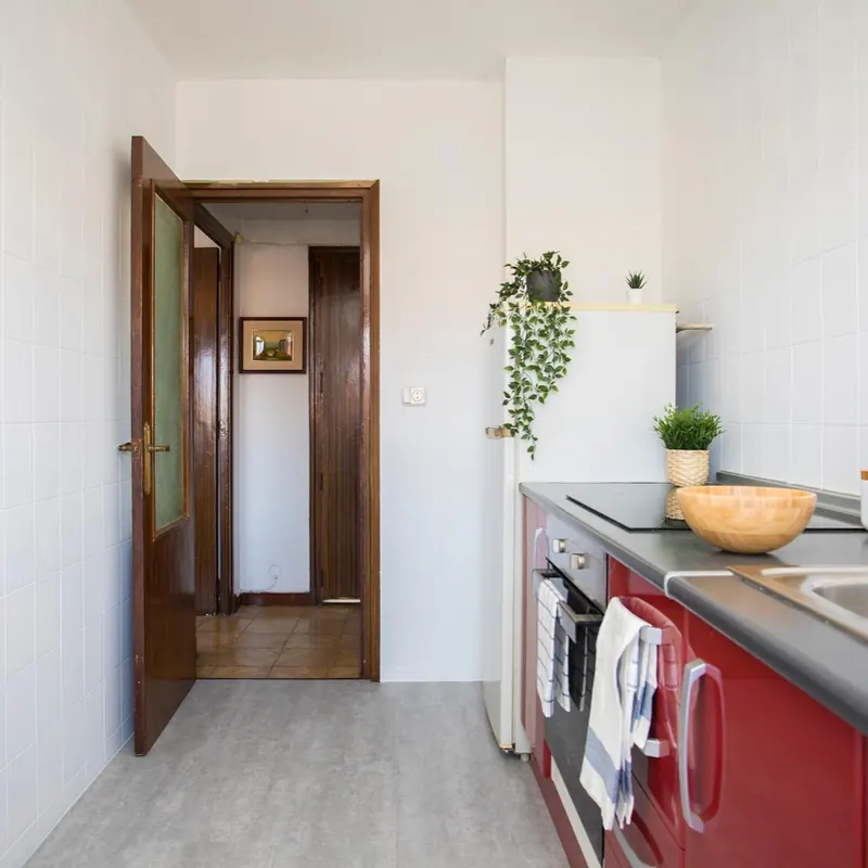 Cocina reformada con muebles rojos y encimera gris