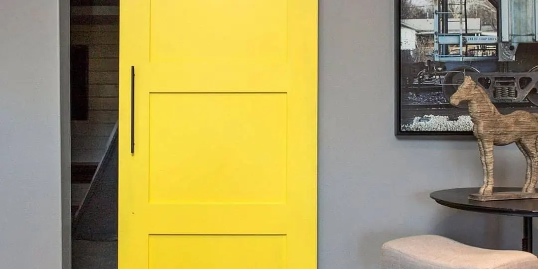 Puerta corredera amarilla de granero instalada en una reforma interior