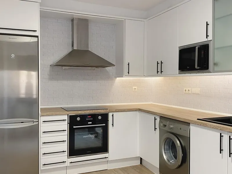 Cocina reformada con muebles blancos y encimera de madera